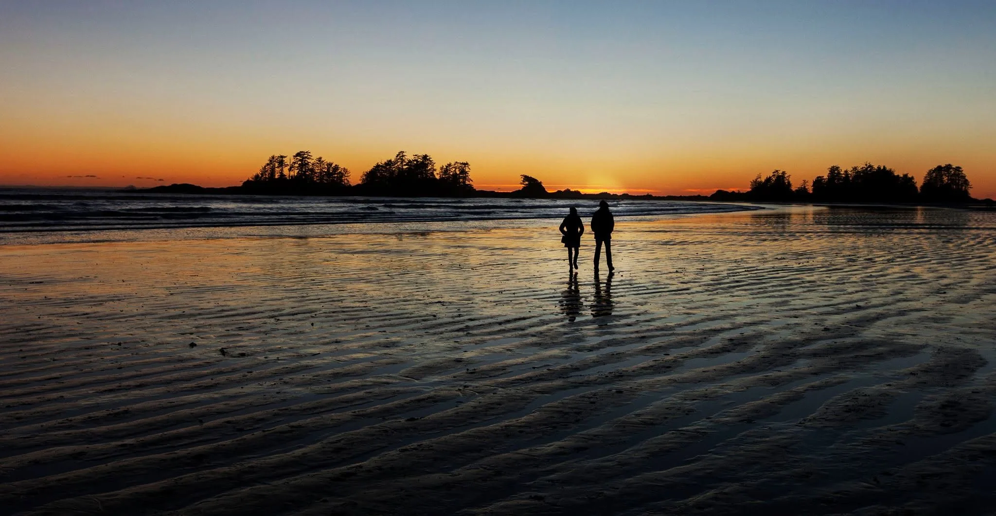 Owen and Megan standing together in shallow water at sunset